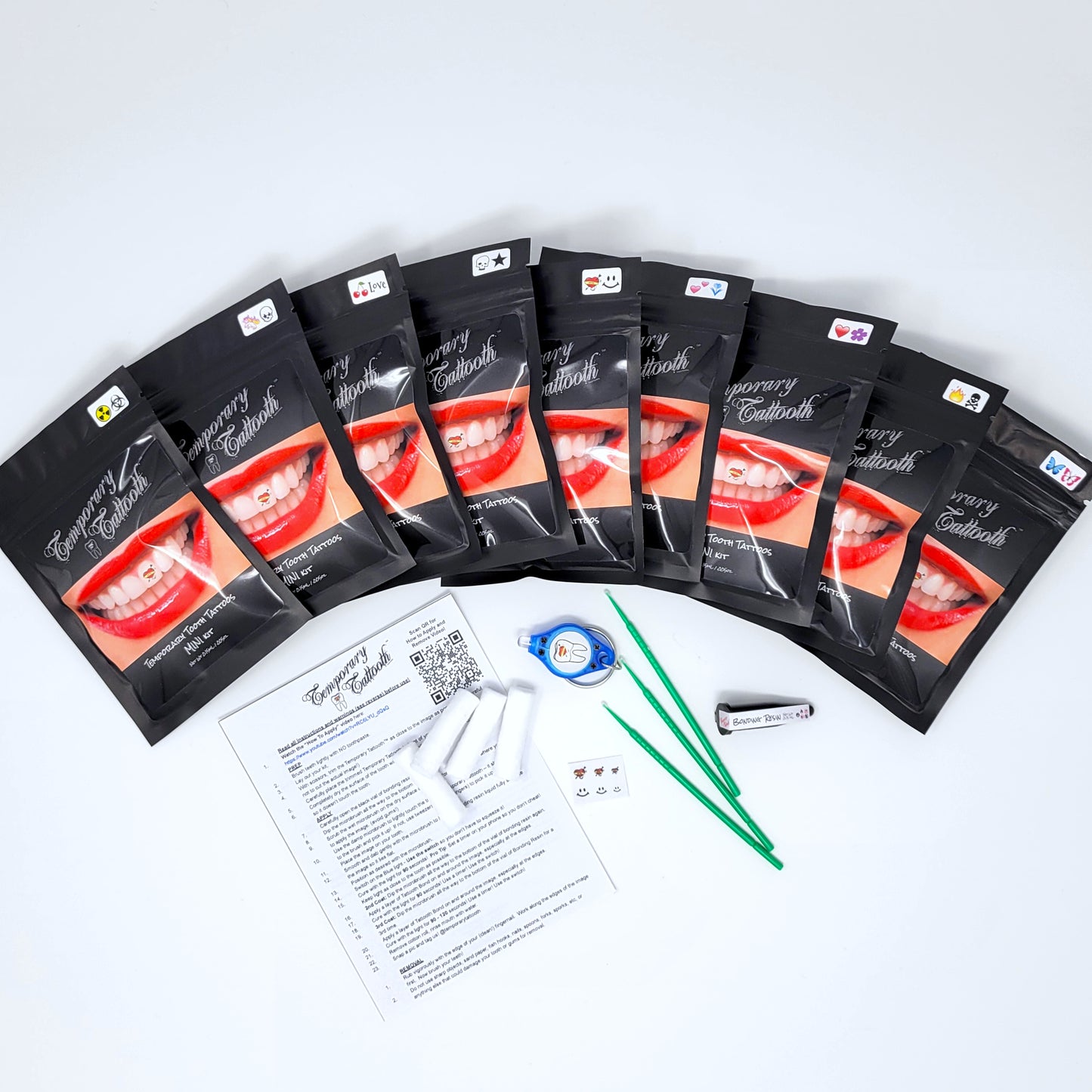 This image shows multiple Temporary Tattooth MINI kits in a line. It also shows the contents of one kit that can be used to apply temporary tooth tattoos to teeth. The packages show the currently available tattooth mini kit designs.