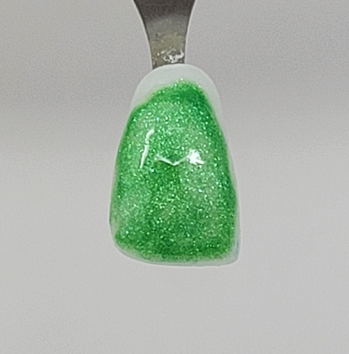 Green Clover Temporary Tattooth Colorant on a demo tooth.  These colorants can be applied to teeth to temporarily alter their color or iridescence.