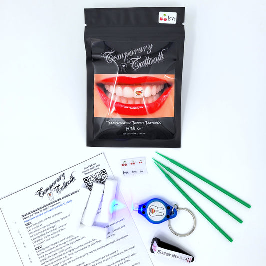 An image of a Temporary Tattooth MINI kit and the contents of the mini kit.  It shows the instructions, cotton rolls, microbrushes, a curing light, bonding resin and a tattooth sheet.  This kit allows you to apply temporary tooth tattoos at home.