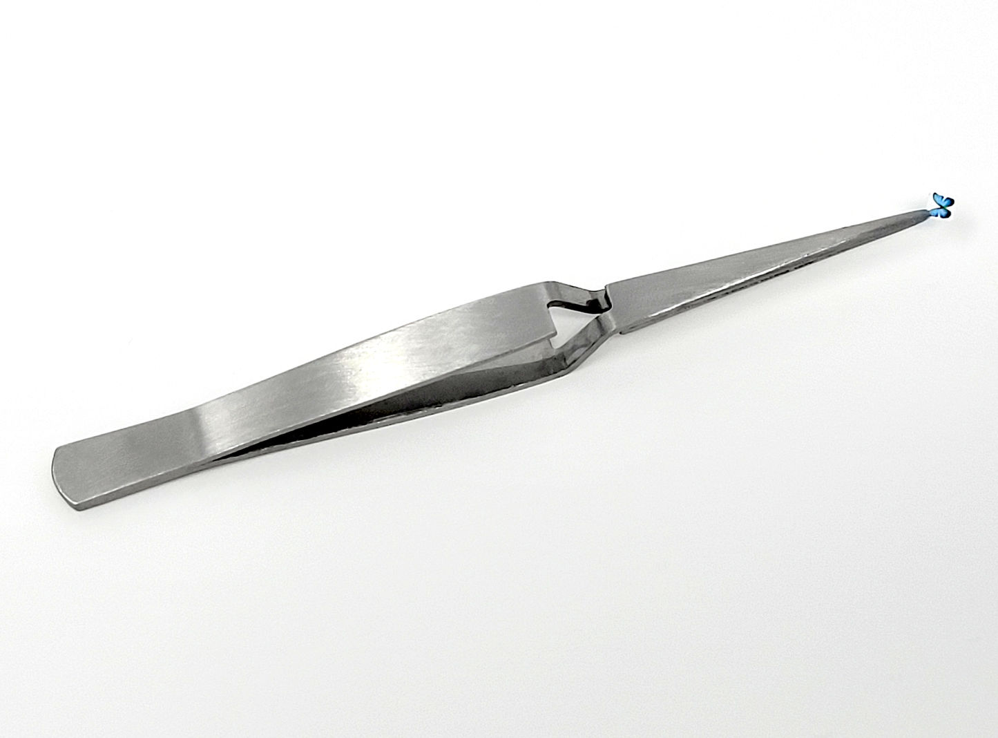 A photograph of reverse tweezers holding a pre-cut Temporary Tattooth image of a butterfly.  These reverse tweezers make applying temporary tattoos for teeth much easier.